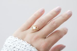 Bague en forme de papillon avec perle de lait maternel au centre, symbole de transformation et de renouveau