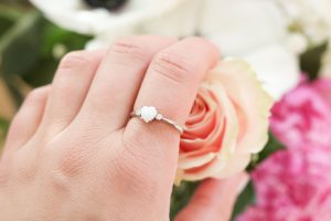 Bague en lait maternel portée à la main, posée délicatement sur une rose.