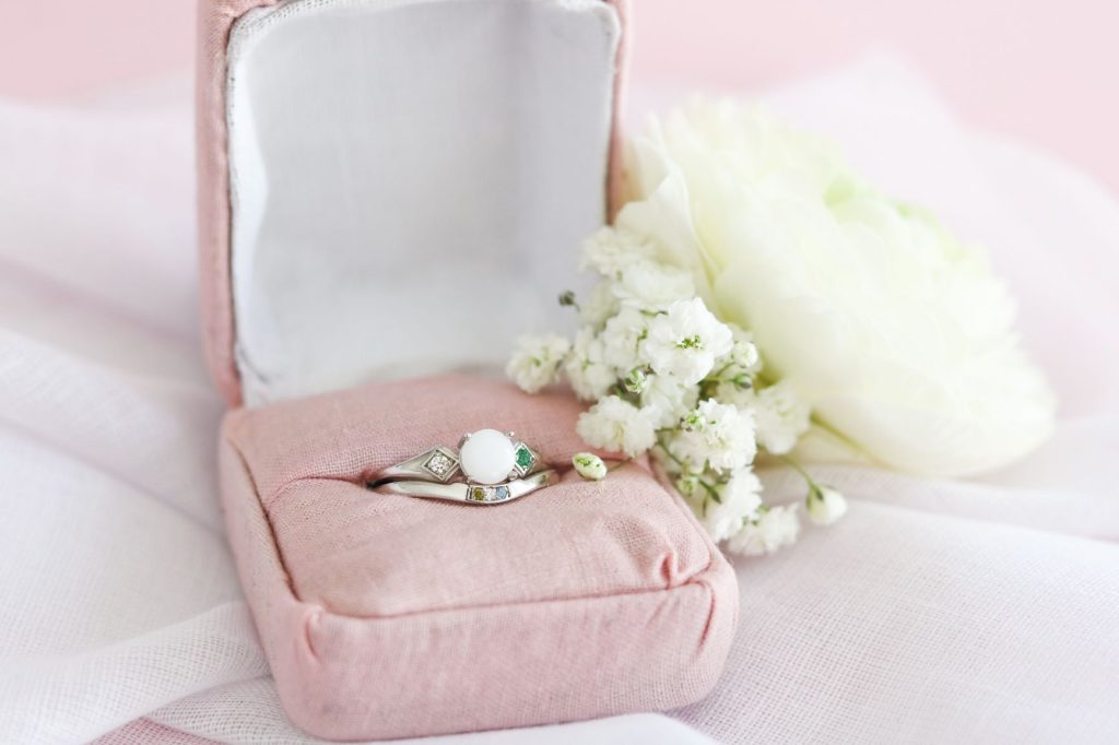 Bague en lait maternel présentée dans un écrin rose avec fleurs blanches.