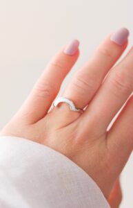 Bague en lait maternel en forme d’arc-en-ciel argenté portée à la main, symbole de renaissance, d’espoir et du parcours maternel