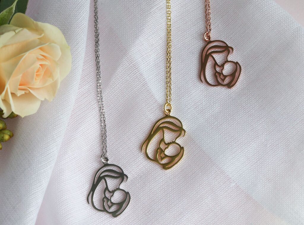Trois pendentifs représentant une mère et son enfant, disponibles en argent, or et or rose.