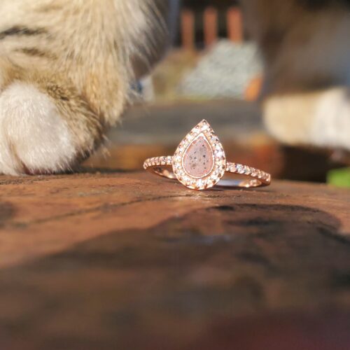 Bague funéraire personnalisée intégrant des cendres et des poils d'animal dans une pierre rose en forme de goutte.
