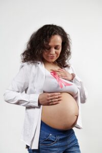 Femme enceinte portant une chemise blanche et un ruban rose en soutien à octobre rose