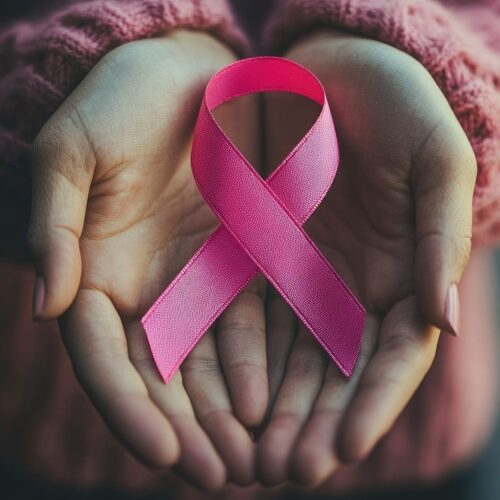Ruban rose dans les mains d'une jeune femme en soutien au cancer du sein