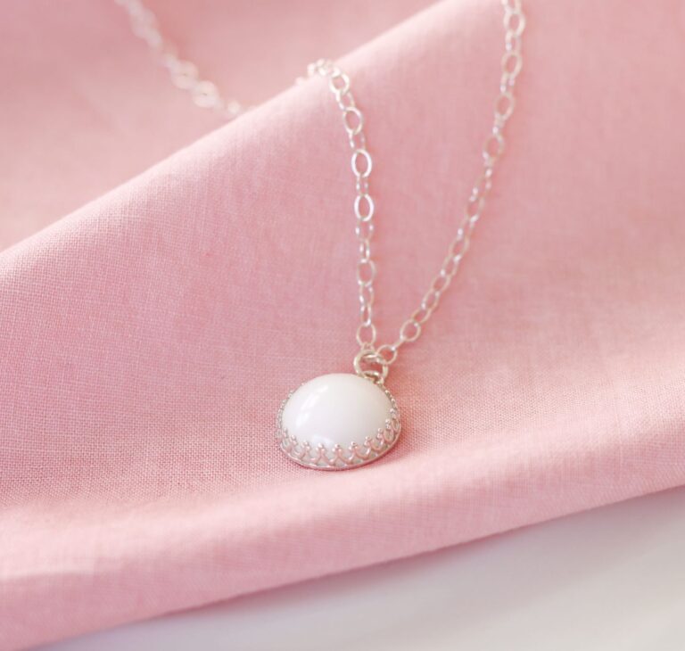 Collier avec perle de lait maternel rode présenté sur un fond rose.