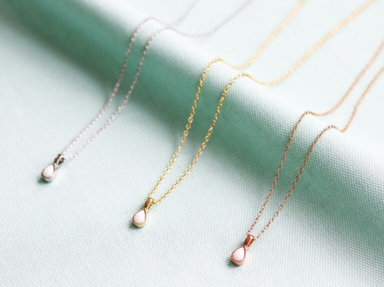 Trois colliers avec perle de lait maternel en forme de goutte, présentés dans trois couleur différentes, or, argent et or rose.