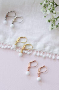 Trois paires de boucles d'oreilles en lait maternel avec perle ronde et pierres de naissance, déclinées en or jaune, or rose et argent.