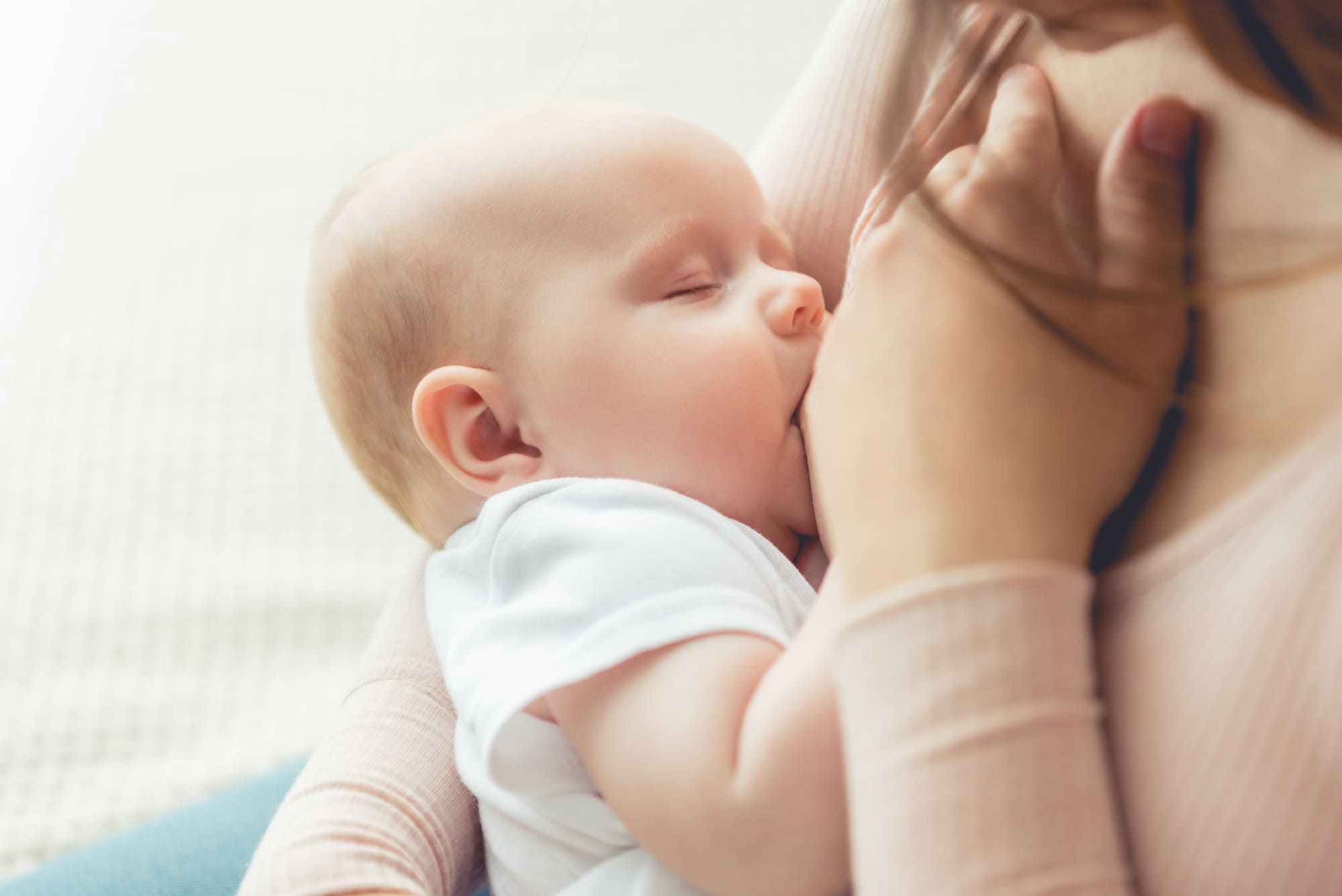 Un bébé fermant les yeux pendant qu'il est allaité par sa maman.
