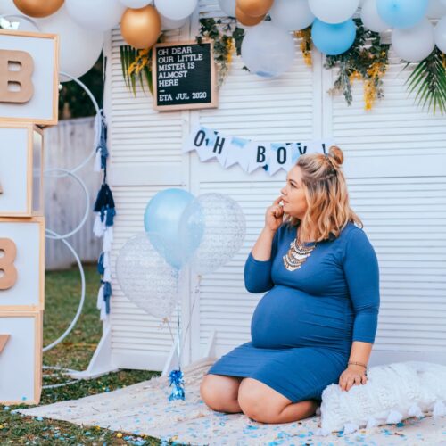 Femme enceinte lors d’un baby shower décoré de ballons bleus et blancs